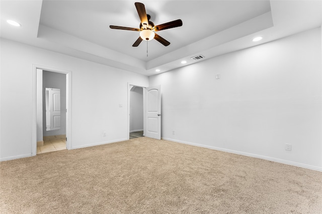 unfurnished bedroom with light colored carpet, a raised ceiling, ceiling fan, and ensuite bathroom