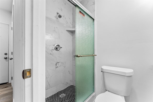 bathroom featuring toilet and a shower with shower door