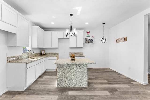 kitchen featuring a kitchen island, stone countertops, pendant lighting, sink, and white cabinets