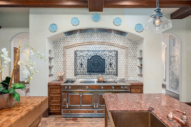 kitchen featuring double oven range, decorative light fixtures, sink, and beam ceiling