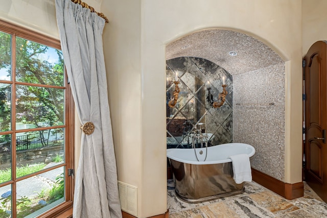 bathroom featuring a bath and tile walls