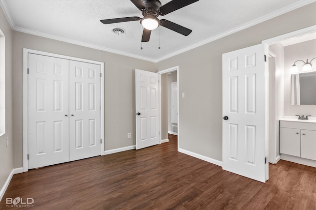 unfurnished bedroom with ensuite bathroom, ceiling fan, ornamental molding, a textured ceiling, and dark hardwood / wood-style flooring