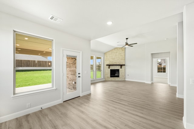 unfurnished living room with a stone fireplace, ceiling fan, light hardwood / wood-style floors, and lofted ceiling