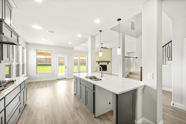 kitchen with pendant lighting, light wood-type flooring, gray cabinetry, and sink