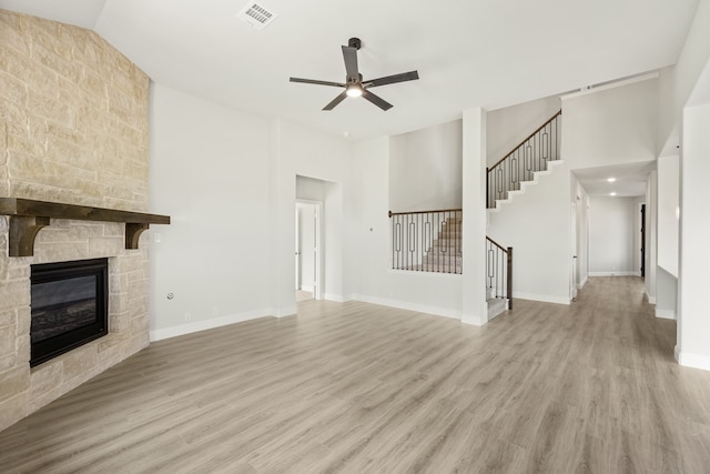 unfurnished living room featuring ceiling fan, light hardwood / wood-style floors, a fireplace, and high vaulted ceiling