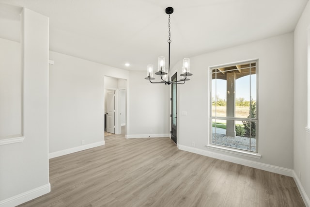 unfurnished dining area with an inviting chandelier and light hardwood / wood-style flooring