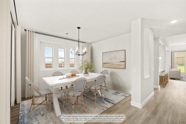 dining area featuring a wealth of natural light, light hardwood / wood-style floors, and an inviting chandelier