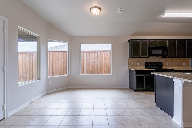 kitchen with tasteful backsplash, light tile patterned flooring, stove, and a healthy amount of sunlight