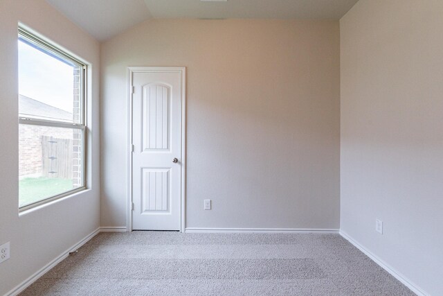 spare room featuring vaulted ceiling and light colored carpet