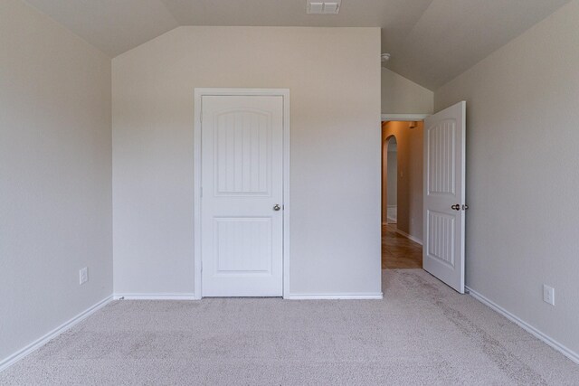 unfurnished bedroom with carpet and vaulted ceiling