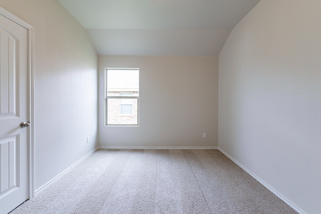 empty room with vaulted ceiling and light colored carpet