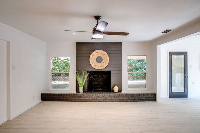 unfurnished living room with ceiling fan, a fireplace, light hardwood / wood-style flooring, and a healthy amount of sunlight