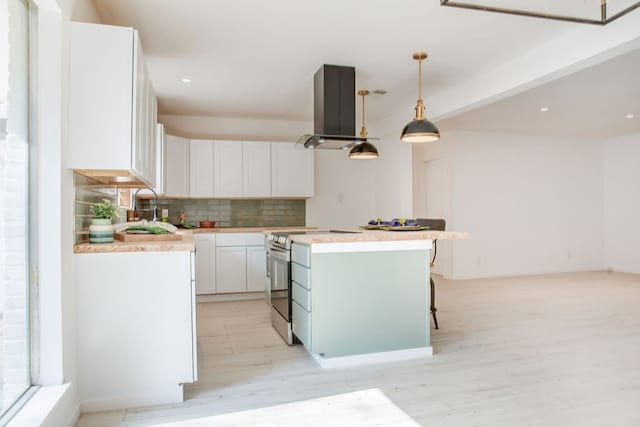 kitchen with island range hood, backsplash, white cabinetry, stainless steel electric stove, and light hardwood / wood-style flooring