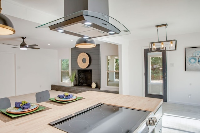 kitchen featuring ceiling fan, a brick fireplace, wooden counters, range, and island range hood