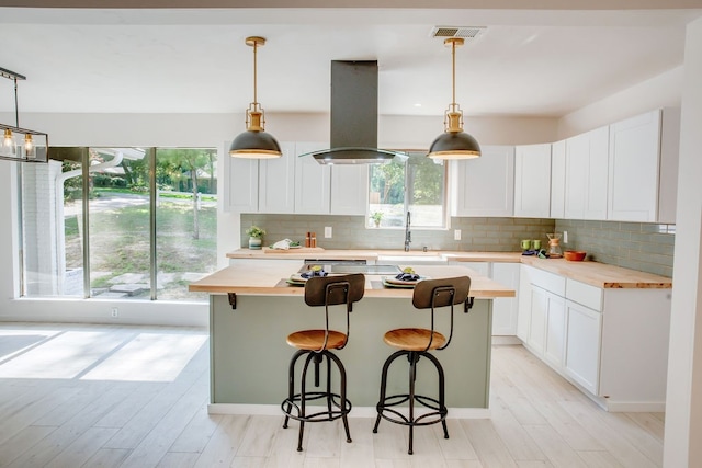 kitchen featuring island range hood, a breakfast bar, a center island, and decorative backsplash