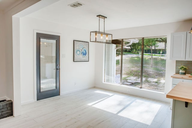 dining area with light wood-type flooring, an inviting chandelier, and a healthy amount of sunlight