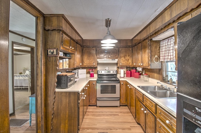 kitchen with a sink, stainless steel appliances, light countertops, under cabinet range hood, and crown molding