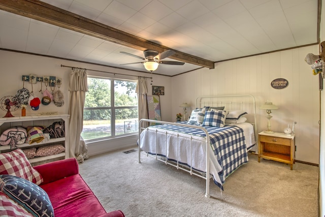 carpeted bedroom with crown molding, beam ceiling, and ceiling fan