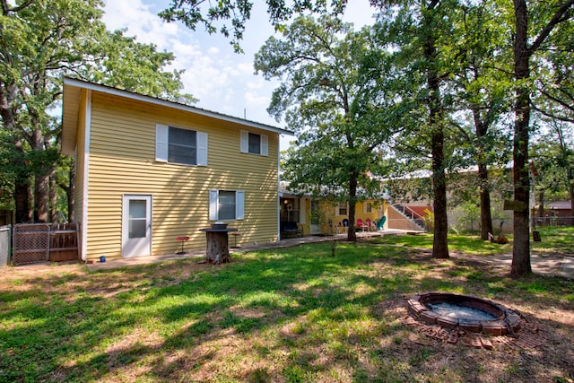 back of house featuring a yard and a fire pit