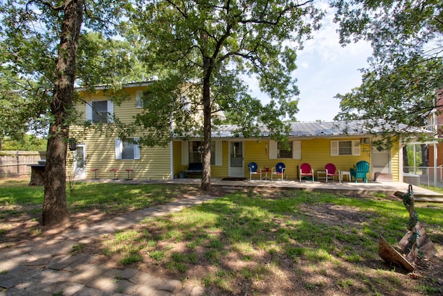 view of front facade featuring a front lawn, metal roof, a patio, and fence