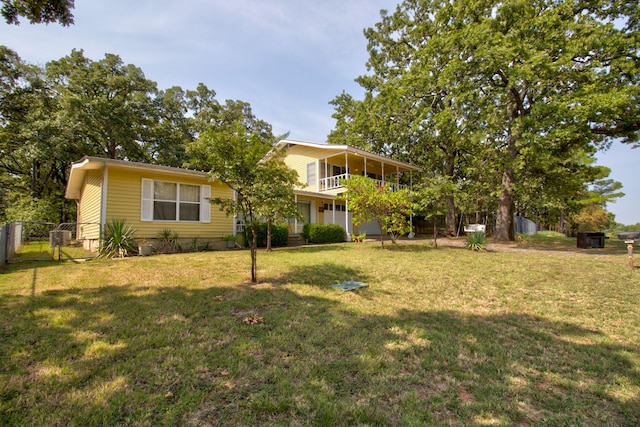 view of front of property featuring a balcony, fence, a front lawn, and a gate