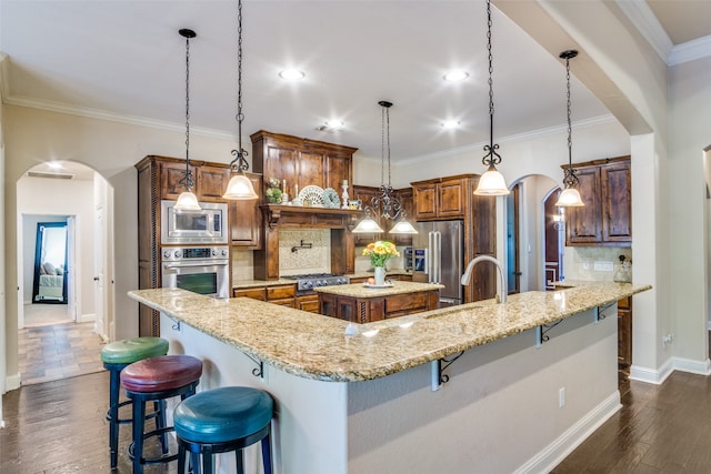 kitchen featuring hanging light fixtures, stainless steel appliances, sink, a spacious island, and a kitchen breakfast bar