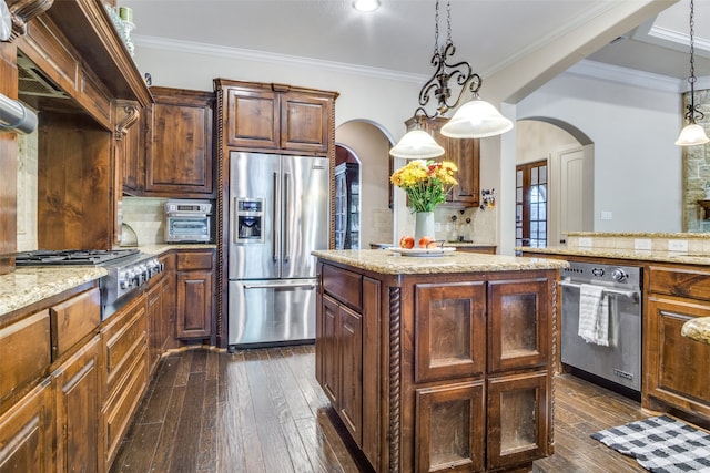 kitchen with a kitchen island, light stone countertops, dark hardwood / wood-style flooring, pendant lighting, and stainless steel appliances