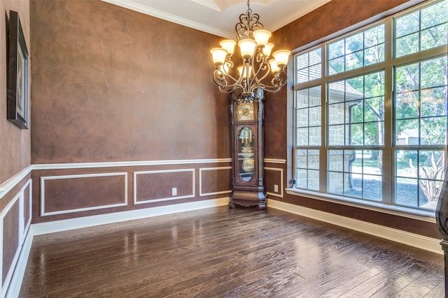 spare room with dark hardwood / wood-style flooring, ornamental molding, and a chandelier