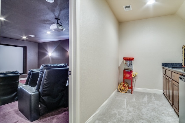 carpeted home theater room featuring vaulted ceiling