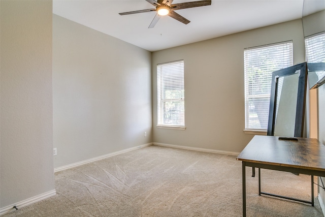 unfurnished office with plenty of natural light, ceiling fan, and light carpet