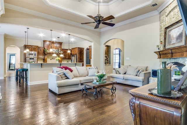 living room featuring ceiling fan, a fireplace, dark hardwood / wood-style floors, and crown molding