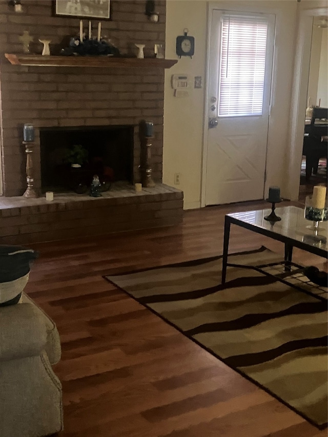 living room with dark hardwood / wood-style floors and a brick fireplace