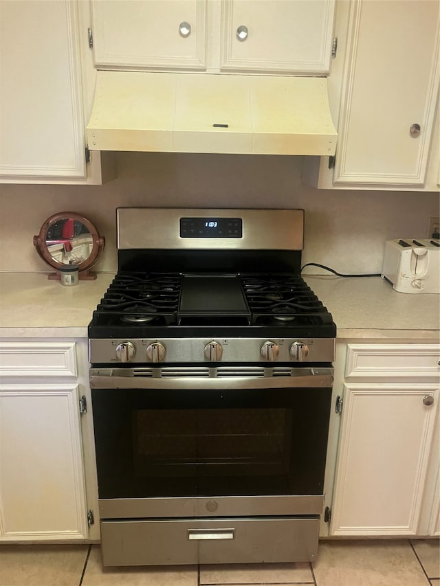 kitchen featuring light tile patterned floors, white cabinets, custom range hood, and stainless steel range with gas cooktop