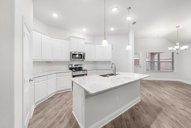 kitchen featuring appliances with stainless steel finishes, white cabinetry, light stone countertops, and sink