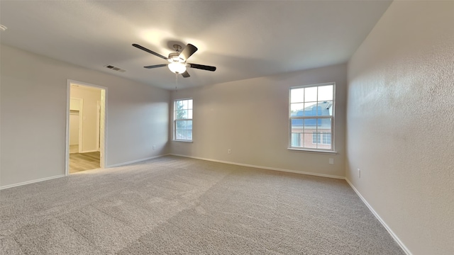 unfurnished room with visible vents, ceiling fan, light carpet, and baseboards