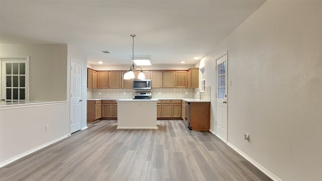 kitchen with backsplash, stove, light wood-type flooring, and decorative light fixtures