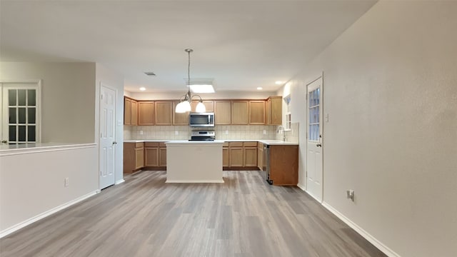 kitchen featuring stainless steel appliances, light countertops, light wood-style flooring, and tasteful backsplash