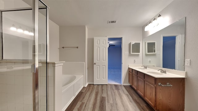 bathroom featuring a stall shower, visible vents, a bath, wood finished floors, and a sink