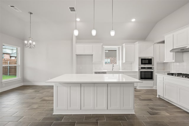 kitchen with decorative backsplash, appliances with stainless steel finishes, pendant lighting, and a kitchen island