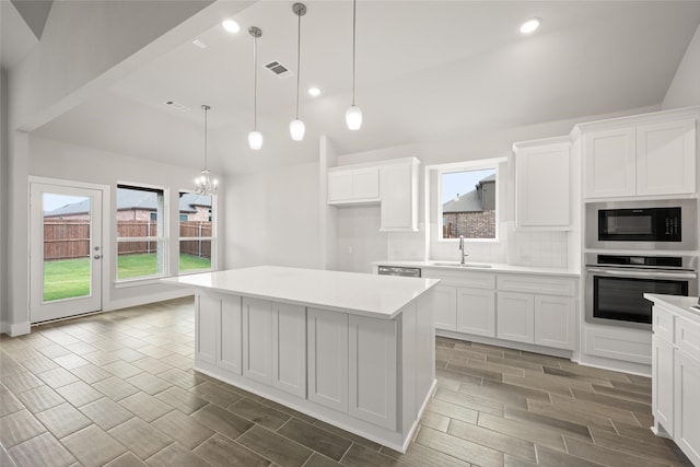 kitchen with white cabinetry, black microwave, oven, tasteful backsplash, and a wealth of natural light