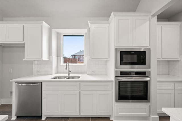 kitchen with sink, decorative backsplash, white cabinetry, and stainless steel appliances