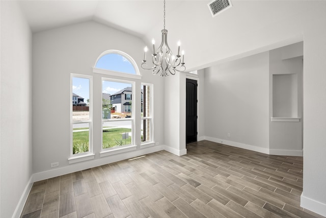 unfurnished dining area with a notable chandelier, vaulted ceiling, and hardwood / wood-style floors