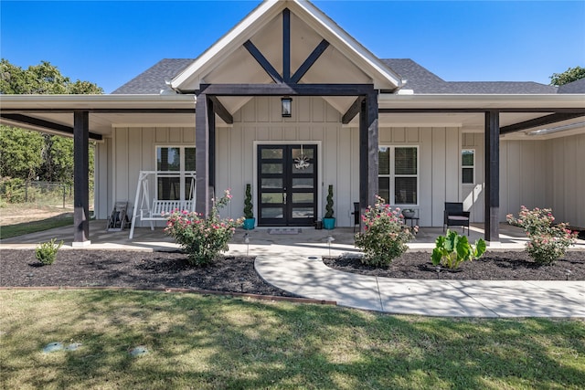 doorway to property featuring covered porch and a lawn