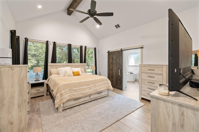 bedroom with light hardwood / wood-style flooring, ceiling fan, a barn door, connected bathroom, and beam ceiling