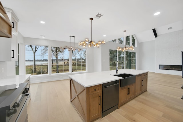 kitchen with pendant lighting, dishwasher, sink, and a center island with sink