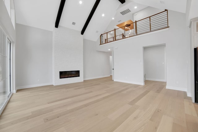 unfurnished living room with high vaulted ceiling, a fireplace, beamed ceiling, ceiling fan, and light hardwood / wood-style floors