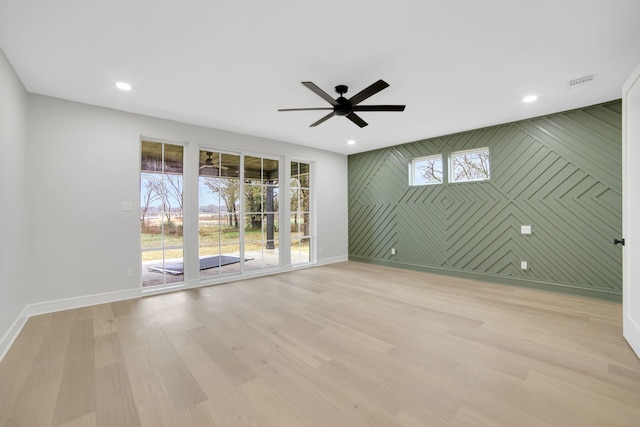 spare room with plenty of natural light, ceiling fan, and light hardwood / wood-style flooring