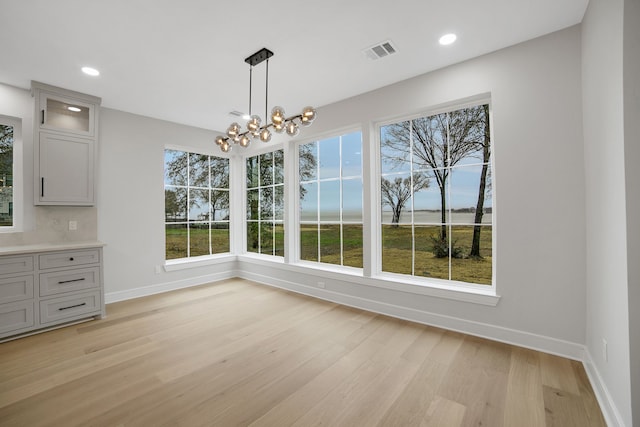 unfurnished dining area featuring a notable chandelier and light hardwood / wood-style floors