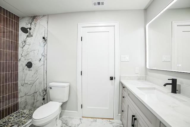 bathroom with vanity, tiled shower, and toilet