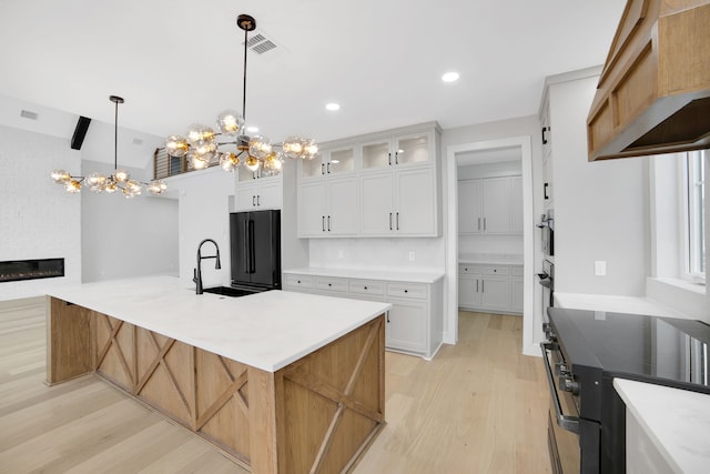 kitchen featuring black refrigerator, white cabinetry, hanging light fixtures, a large island, and electric range